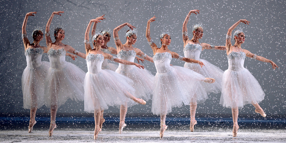 Snow falls as eight Snowflakes jump right, looking left, right legs down, left legs and arms out, right arms curved overhead
