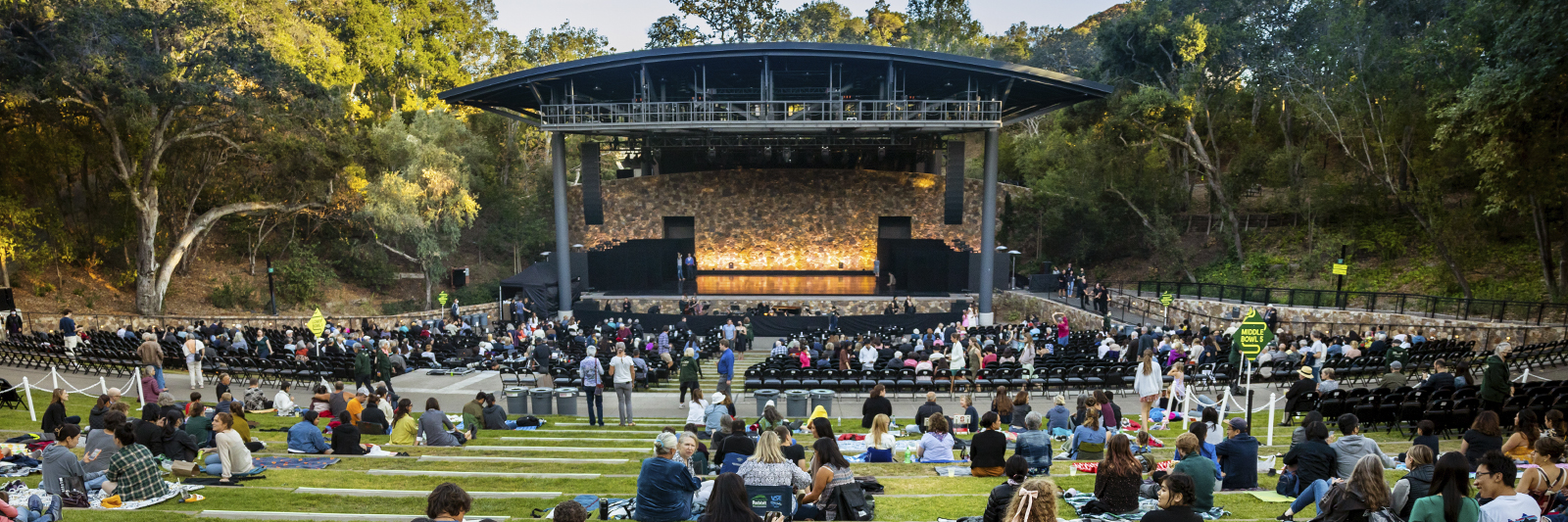 An image of an outdoor concert with people sitting in the grass