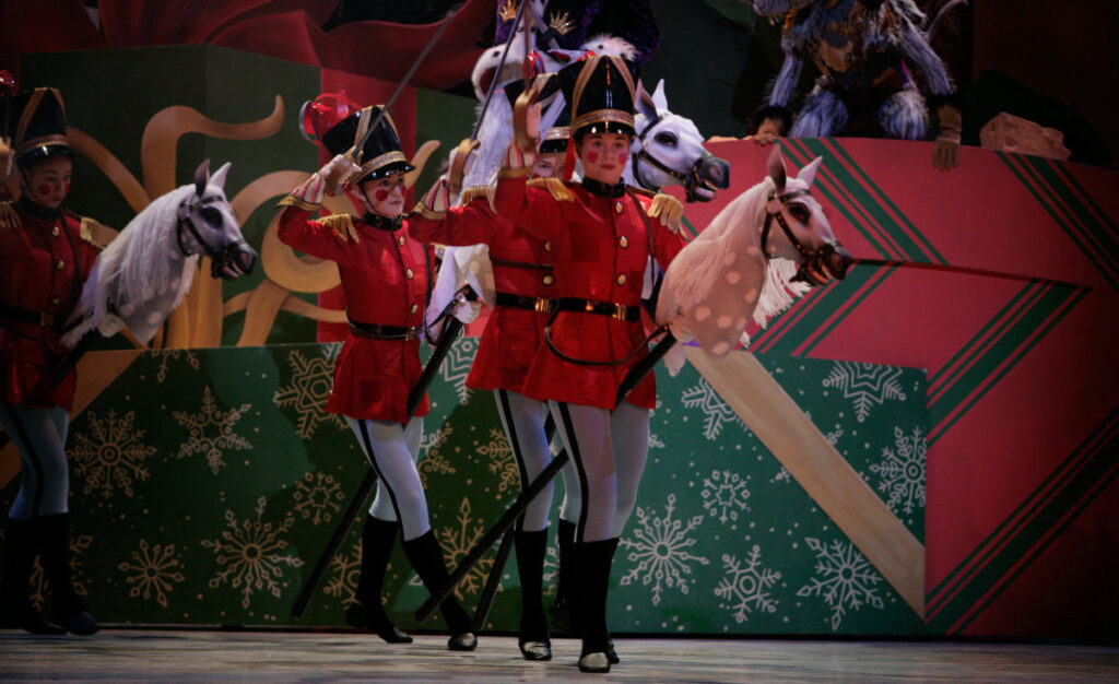 Toy soldiers armed with swords ride hobby horses.