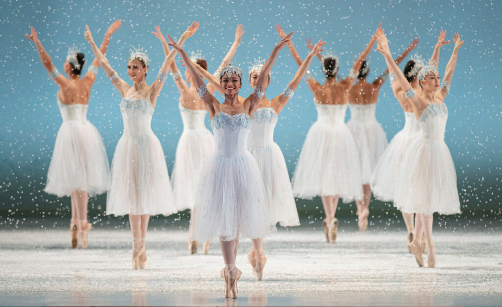 Ballerinas in snowflake costumes dancing in formation.